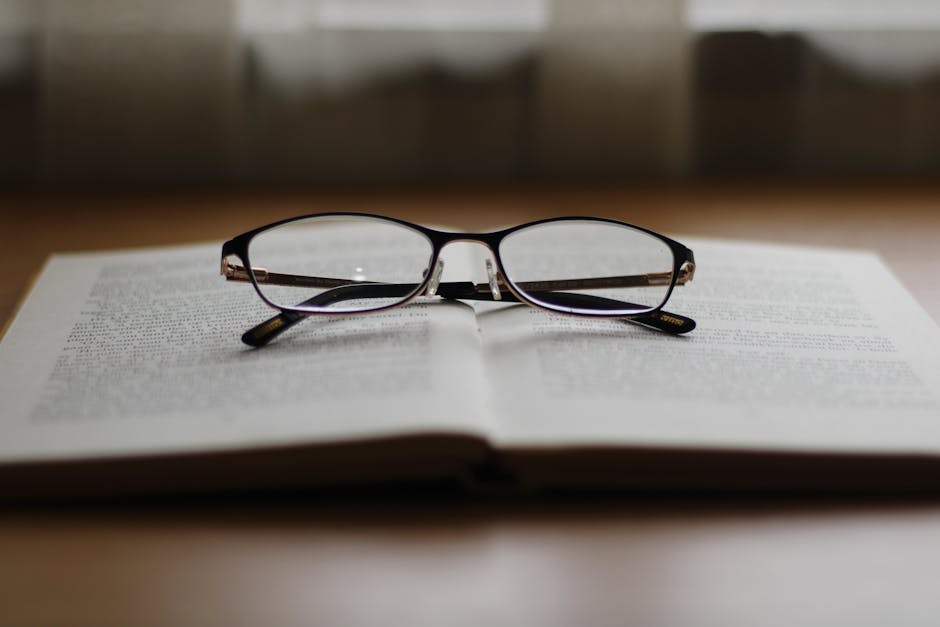 A pair of reading glasses resting on an open book, creating a cozy reading ambiance.