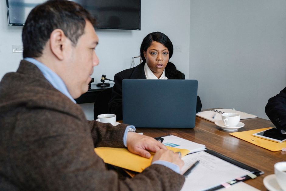 Group of multiethnic coworkers in formal wear sitting at table with laptop and documents while discussing business issues