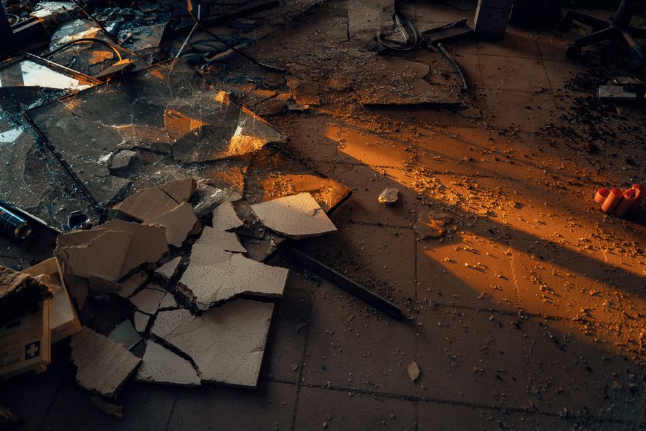 A dramatic scene of shattered glass and debris in warm lighting, symbolizing urban decay.