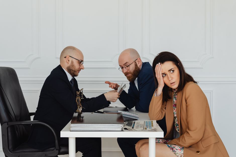 Two lawyers discuss documents with a worried client in a professional office setting.